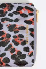 Monedero pequeño con estampado animal print en tonos lila, negro y naranja. Tiene cierre con cremallera dorada y logo de la marca en el frente. Interior con tarjetero y forro con logo grabado.