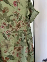 Vestido midi verde con estampado floral, confeccionado en lino italiano, con escote redondo y mangas tres cuartos con botón ajustable.