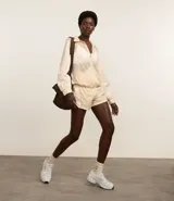 Campera deportiva femenina, modelo rompevientos, confeccionada en poliamida, con cuello alto y puños ajustados. Sin estampa, tiene cierre delantero con cremallera y recortes con hilo reflectante.