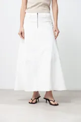 Maxi falda blanca de jean con corte evasé, cintura alta y cierre frontal con cremallera.