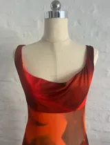 Vestido largo de microtul estampado en tonos naranja y marrón, con escote drapeado, breteles finos y tajo lateral.
