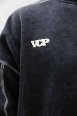 Buzo negro de frisa 100% algodón con calce oversize y lavado gastado. Presenta costuras a contratono, recortes y logos estampados en el frente y en el puño.