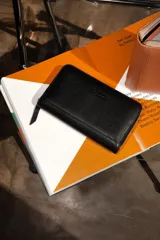 Billetera negra de cuero con cierre de cremallera, múltiples ranuras para tarjetas, compartimento para billetes y monedero con cremallera.