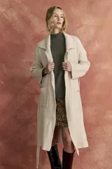Saco largo tejido color beige, con cuello tipo solapa, bolsillos delanteros y cinturón del mismo tejido.
