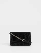Bandolera negra de cuerina con textura croco, solapa con broche a presión y correa de cadena metálica plateada con charm lateral.