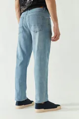Pantalón de jean celeste de corte recto, con cintura regular y tiro medio. Presenta un pequeño agujero en la rodilla derecha y logo bordado en el bolsillo delantero. Confeccionado en algodón con spandex.