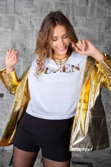 Remera blanca de algodón con cuello redondo y estampado dorado con la palabra "Queen" en el frente. Corte recto y mangas cortas.