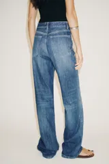 Pantalón de jean rígido celeste con tiro alto, cinco bolsillos, trabillas en la cintura, pierna ancha y largo hasta el tobillo.