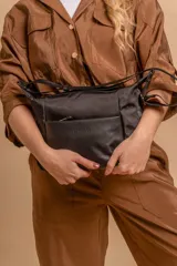 Bandolera de diseño moderno, color beige rosado, con correa regulable y bolsillo frontal con cierre.