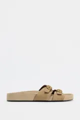 Sandalia plana color beige de serraje con doble tira delantera y hebillas.