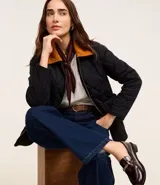 Campera puffer negra con cuello de terciopelo color mostaza, cierre frontal con cremallera y bolsillos laterales.
