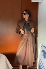 Falda midi marrón de cuero sintético, corte evasé, con cinturón con hebilla circular.