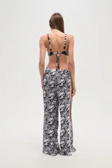 Pantalón largo de tela fluida con estampado de cebra en tonos rosa y fucsia. Tiene corte ancho y aberturas laterales con detalle de argollas.