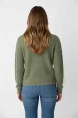 Sweater de punto acrílico color crema, con diseño de trenzas en el cuerpo y mangas, cuello redondo y calce holgado.