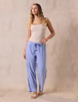 Pantalón largo de lino y rayón a rayas verticales grises y blancas. Tiene pretina elastizada con lazo de ajuste, bolsillos delanteros y traseros.