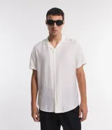 Camisa boxy de hombre confeccionada en viscolino color crudo con rayas texturizadas, cuello inglés, solapa, mangas cortas y abotonado frontal.