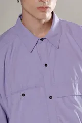 Camisa celeste de manga corta con doble bolsillo y ojal delantero con solapa en uno de ellos. Tiene calce oversize y está realizada en tejido plano suave al tacto.