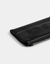 Billetera negra de cuerina con formato fichero y solapa bordada. Cuenta con sistema de apertura con broche a presión y compartimentos para tarjetas y billetes.