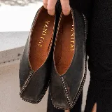 Zapato bajo de cuero negro con punta cuadrada y detalle de cierre en la capellada. Interior forrado en cuero color suela y suela de madera con inclinación de 0,5 cm.