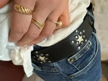 Cinturón negro de cuero con hebilla plateada y apliques de estrellas plateadas.