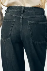 Pantalón de jean de tiro alto color gris oscuro, corte recto, con bolsillos delanteros y traseros. Cierre frontal con cremallera y botón.