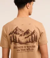 Remera color beige de algodón, corte comfort, con cuello redondo y mangas cortas. Presenta estampa de montañas y texto "Silence is louder in the wild".