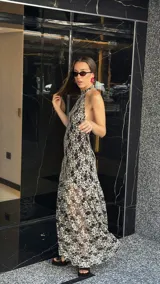 Vestido midi de encaje floral color beige sobre base negra, con cuello halter y falda con vuelo.