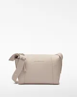 Bandolera mediana color beige de poliéster y poliuretano, con interior a contraste, un compartimento y cierre de cremallera. Asa larga regulable con hebilla metálica y logo grabado.