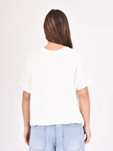 Remera blanca de corte recto con estampado de flores rojas y texto azul "PROFUMO DI FIORI".