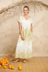 Vestido largo color blanco con estampado floral en tonos verdes y amarillos, con escote en V y mangas cortas.