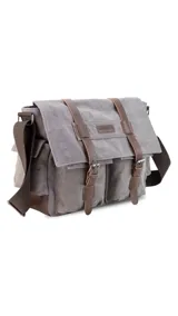 Morral de tela canvas color gris con detalles en cuero marrón. Tiene tapa con hebillas, doble bolsillo frontal, trasero y laterales. Interior espacioso con compartimento para notebook de 15". Correa de galón regulable para mayor comodidad.