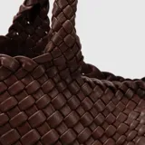 Bolso tote color marrón con diseño trenzado y doble asa de hombro. Incluye un estuche interior desmontable con cierre.
