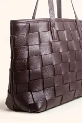 Cartera tipo tote bag de cuero vacuno trenzado a mano, con diseño de tejido ajedrez. Cuenta con doble asa de hombro y cierre superior.