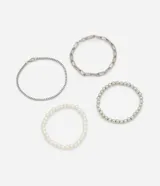 Set de cuatro pulseras: una de cadena fina plateada, una de eslabones alargados plateados, una de perlas blancas y una de esferas metálicas plateadas.