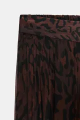 Pantalón bombacho de tiro medio, color marrón oscuro con estampado animal print negro. La tela es semitransparente y presenta un efecto plisado o texturizado. El bajo de la pierna termina en un puño elástico.