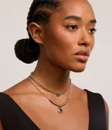 Collar de capas dorado con colgantes de resina verde y negra.
