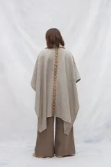 Poncho de lana color marrón con cuello alto, mangas 3/4 y bolsillo lateral con detalle de botones de cuero.