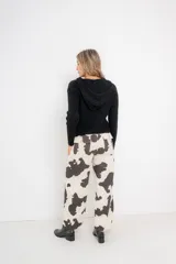 Pantalón jean cargo de denim rígido con estampado de vaca en blanco y negro, tiro alto, bolsillos frontales y traseros funcionales, hebillas metálicas regulables en la cintura.
