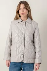 Campera capitoneada color gris claro, confeccionada en cuero ovino italiano con diseño de rombos. Tiene cuello camisero, cierre frontal con botones a presión, bolsillos laterales y forro interior de guata.