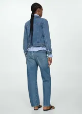 Chaqueta de jean azul de corte clásico con cuello de solapa, cierre frontal con botones metálicos, bolsillos delanteros con solapa y puños abotonados.