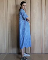 Vestido túnica celeste de lino con rayas verticales blancas, corte recto, cuello camisero y mangas cortas.
