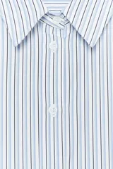 Camisa blanca de popelina de algodón, con cuello solapa y mangas largas con puños abotonados.