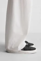 Zapatillas deportivas negras con detalle en blanco en la parte posterior y suela blanca con volumen de diseño irregular.