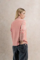 Polera de punto a rayas horizontales color celeste y blanco, de cuello alto y mangas largas.