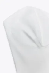 Corsé blanco de popelín de algodón con escote corazón y hombros descubiertos. Presenta costuras marcadas y cierre trasero con cremallera y gancho metálico.