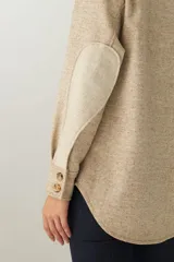 Camisa estilo leñador color beige con textura de espiga, de manga larga con puños abotonados, cuello clásico, cierre frontal con botones y dos bolsillos de parche con solapa abotonada en el pecho.