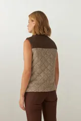 Chaleco corto de lana color marrón con diseño acolchado en forma de rombos. Presenta cuello alto, cierre frontal con cremallera dorada, dos bolsillos laterales y canesú en color marrón oscuro. Hecho en Uruguay.