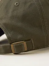 Gorra de gabardina color verde militar con visera curva y logo bordado en el frente. Ajuste trasero con hebilla metálica.