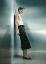 Falda midi negra con cintura elástica, tiro medio, diseño recto y detalle de strass plateado.
