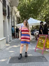 Vestido corto tejido a rayas horizontales en tonos crudo, naranja, rojo, rosa, azul y blanco.